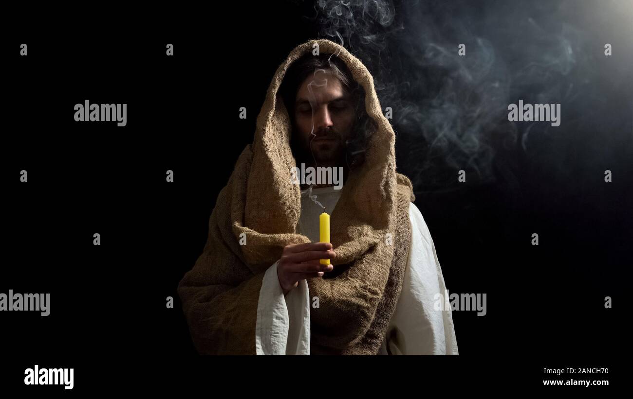 Jesus holding blown candle, praying for people sins expiation, soul salvation Stock Photo