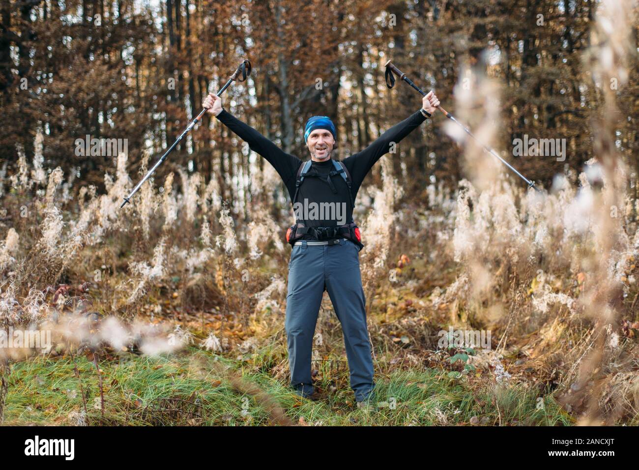 Portrait of happy mature man with trekking poles in autumn forest Stock Photo
