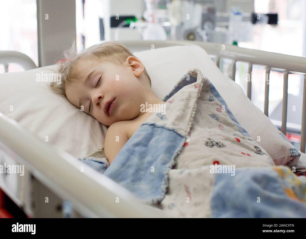 Toddler sleeps on back in hospital bed. Stock Photo