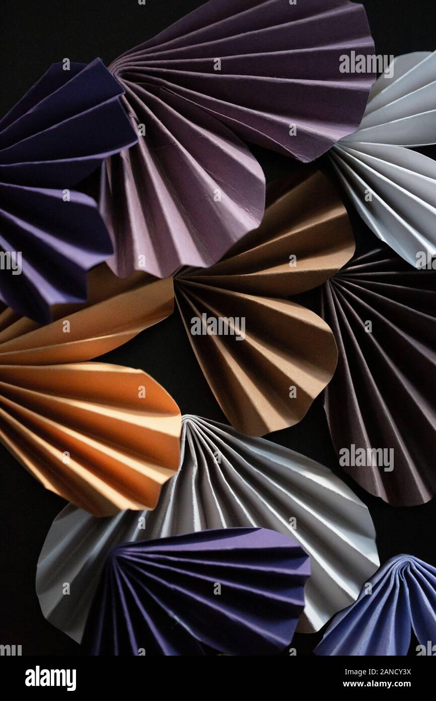 Folded colorful origami hearts arranged against dark background Stock Photo