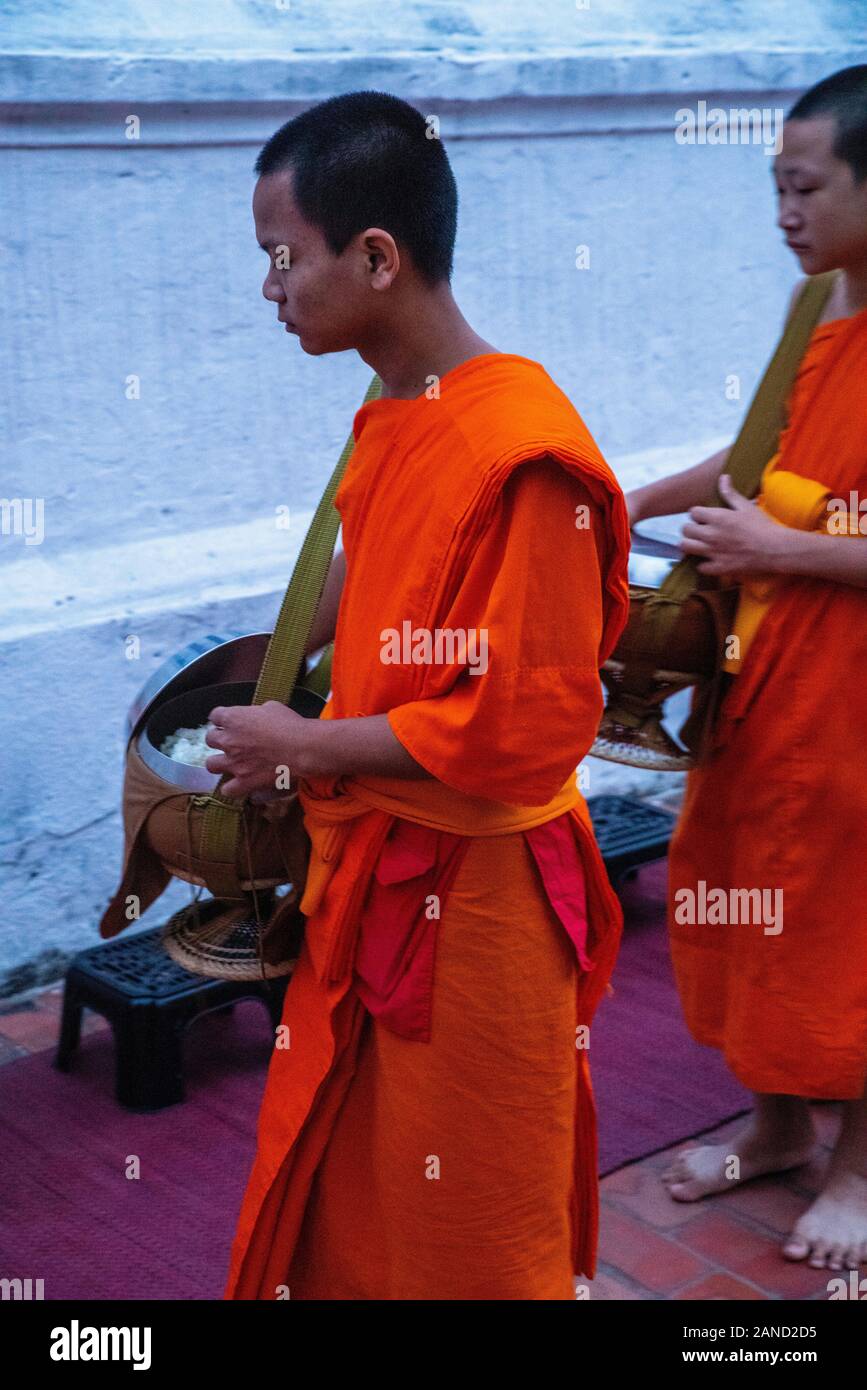 Monks and tourists participate in sai bat (morning alms giving), Luang Prabang, Laos. Stock Photo