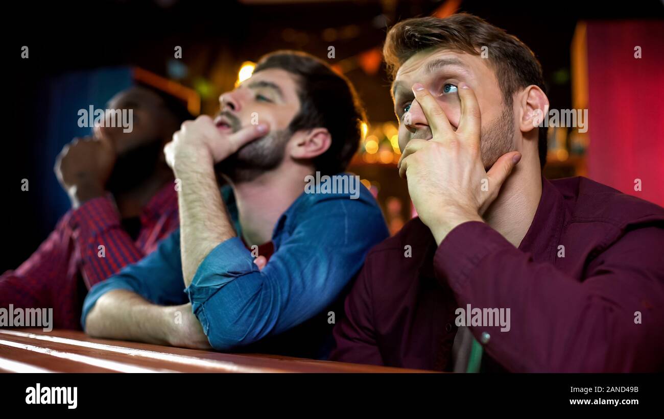 Frustrated male friends upset with favourite team loss in competition, bar Stock Photo