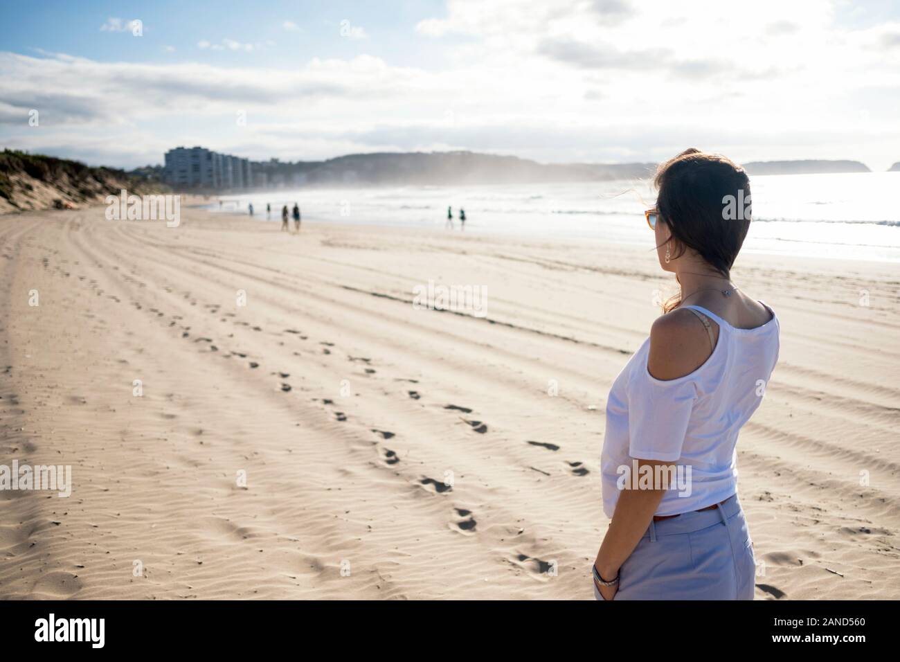 Young woman looking towards Salinas seaside town from Playa de San Juan beach (San Juan de Nieva, El Espartal, Castrillón, Asturias, Spain). High-key Stock Photo