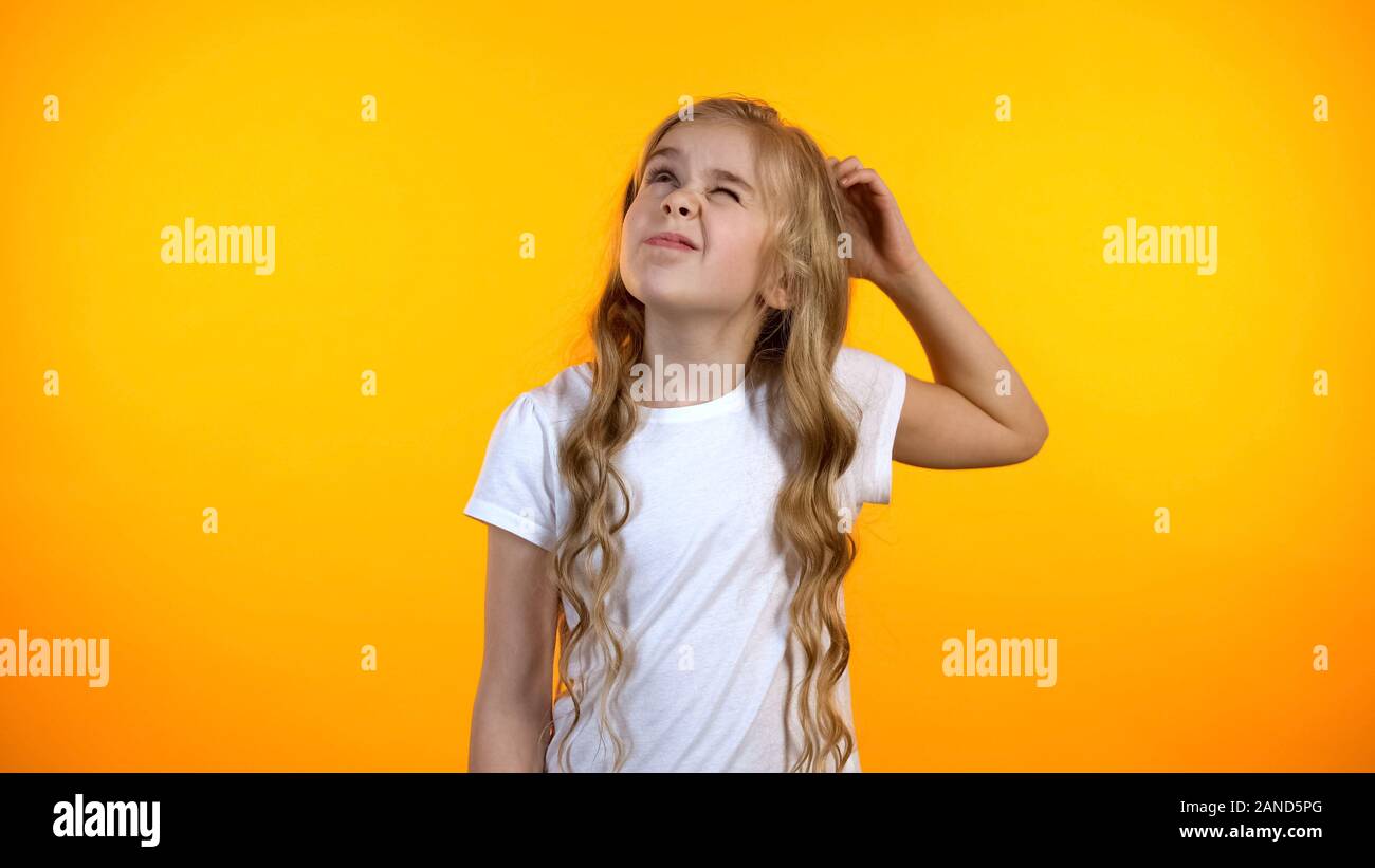 Adorable puzzled girl scratching head, having no ideas, creative child thinking Stock Photo