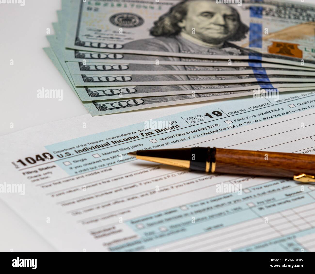 1040 individual income tax return form 2019 with pen and 100 dollar bills. Concept of filing taxes, payment, refund, and April 15,2020 deadline date. Stock Photo