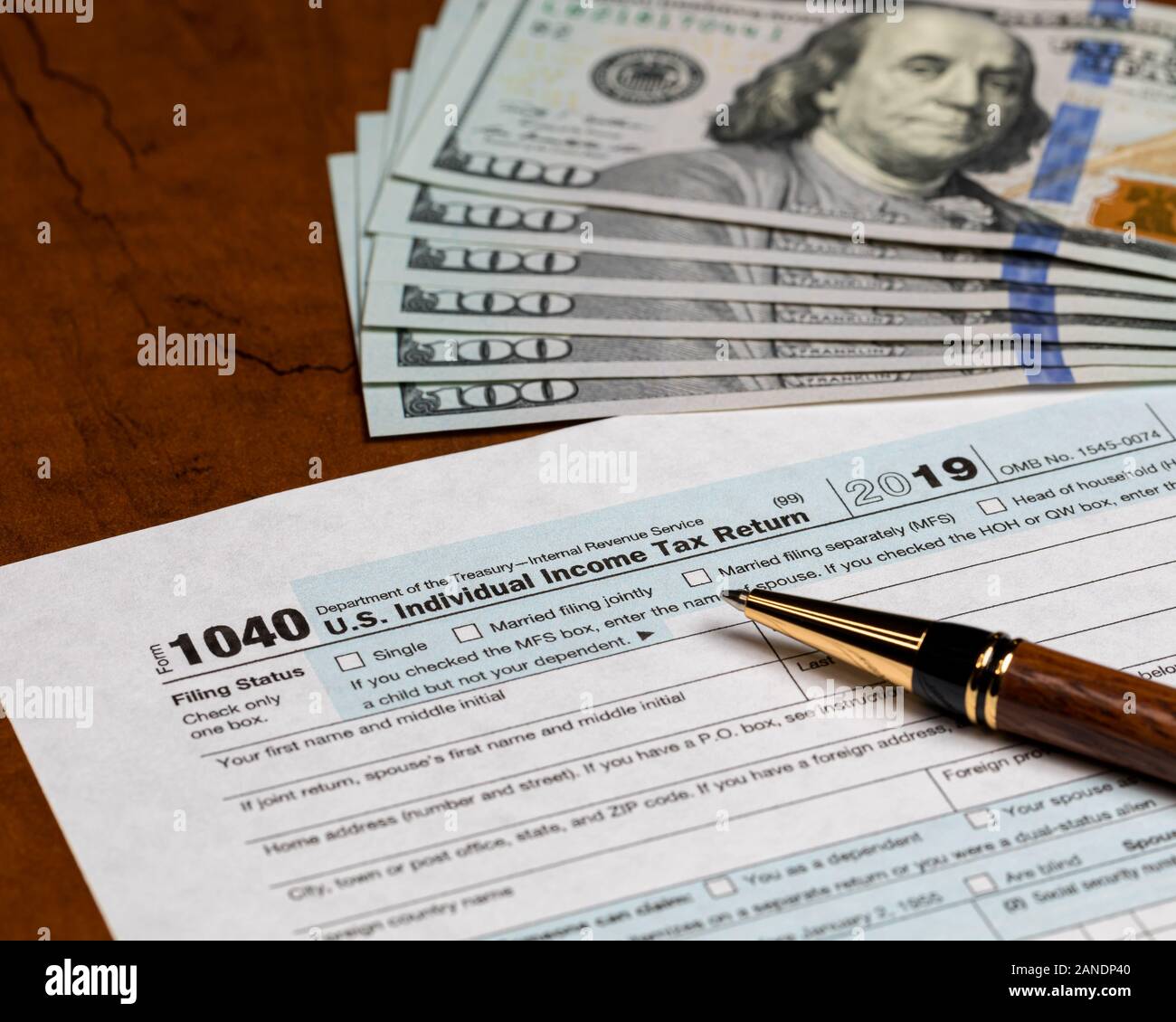 1040 individual income tax return form 2019 with pen and 100 dollar bills. Concept of filing taxes, payment, refund, and April 15,2020 deadline date. Stock Photo