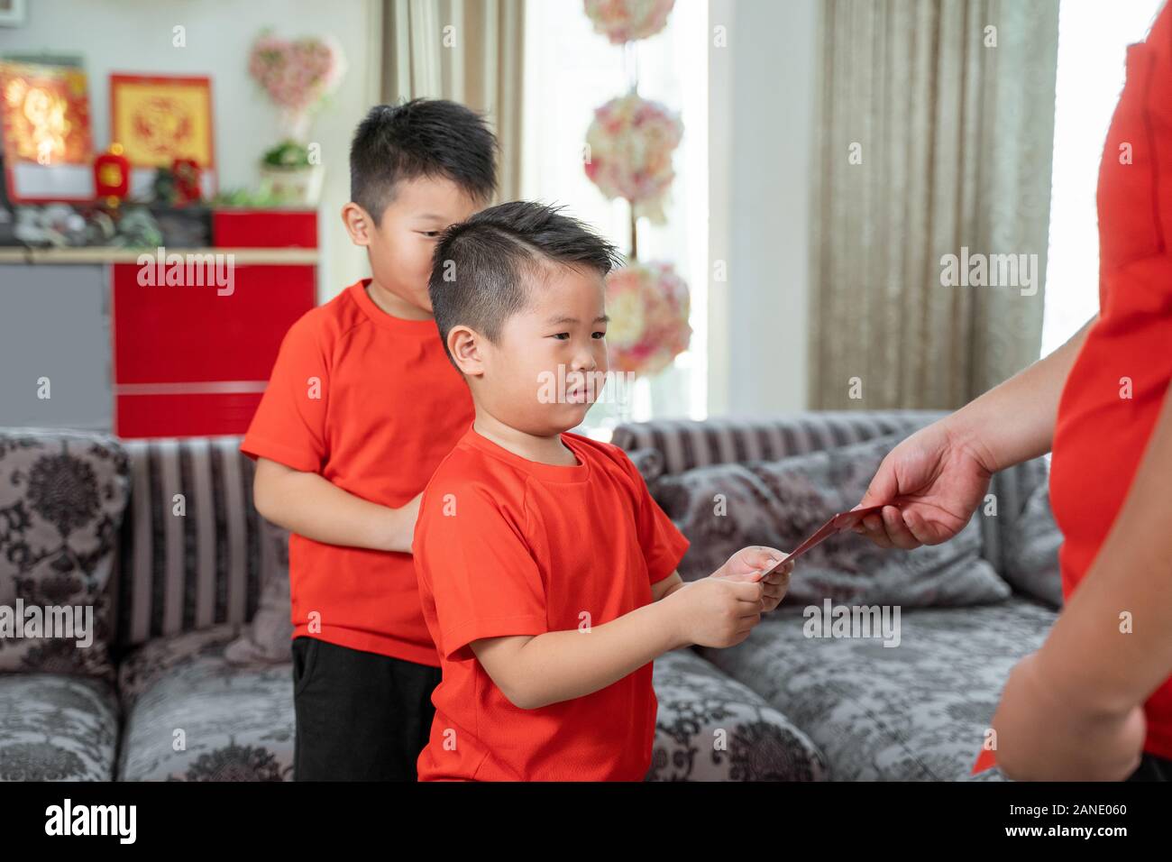 Asian chinese father give ang pao to her sons Stock Photo