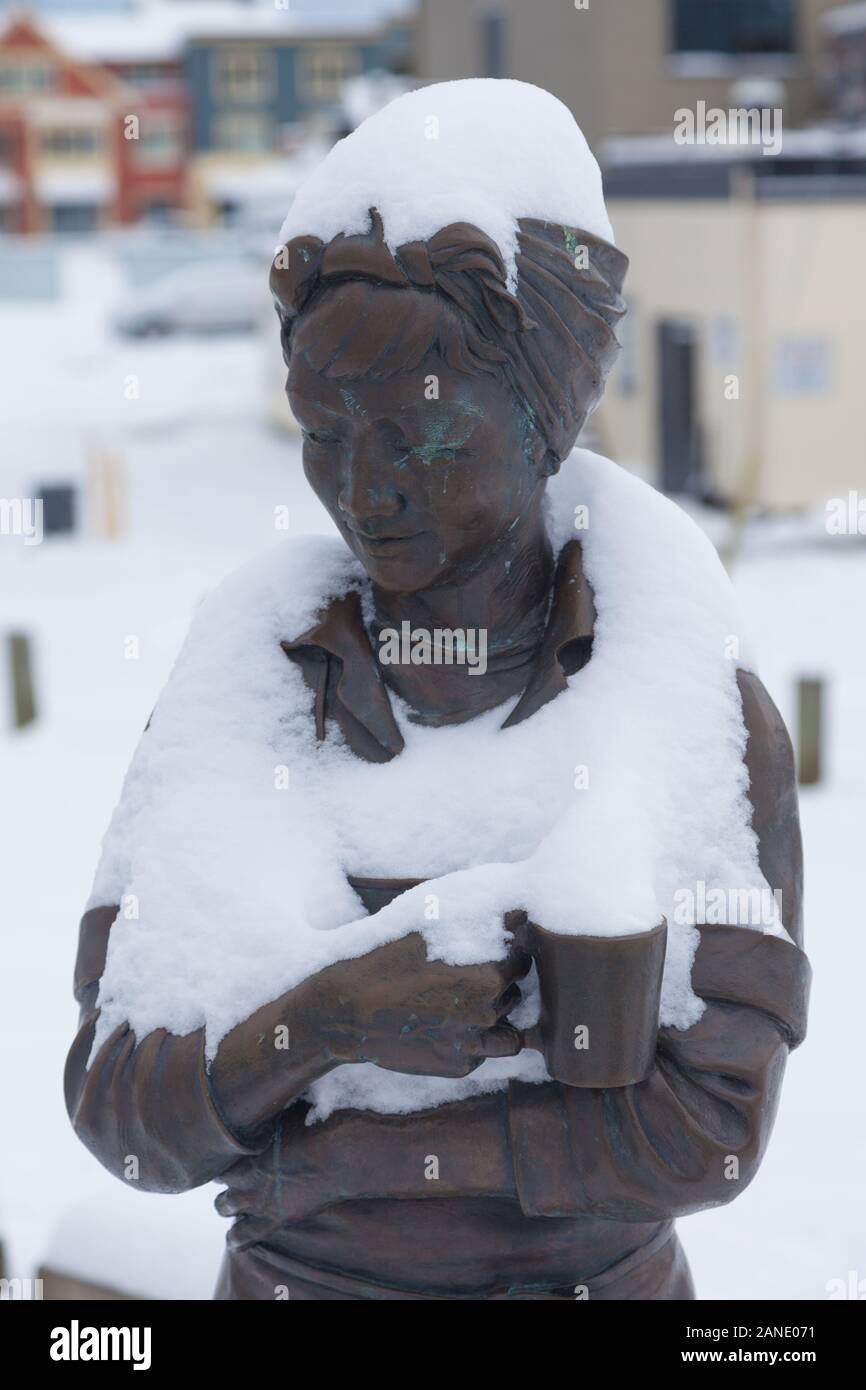 Hertage bronze statue of a fish cannery worker draped in a fresh fall of snow in the village of Steveston British Columbia Stock Photo