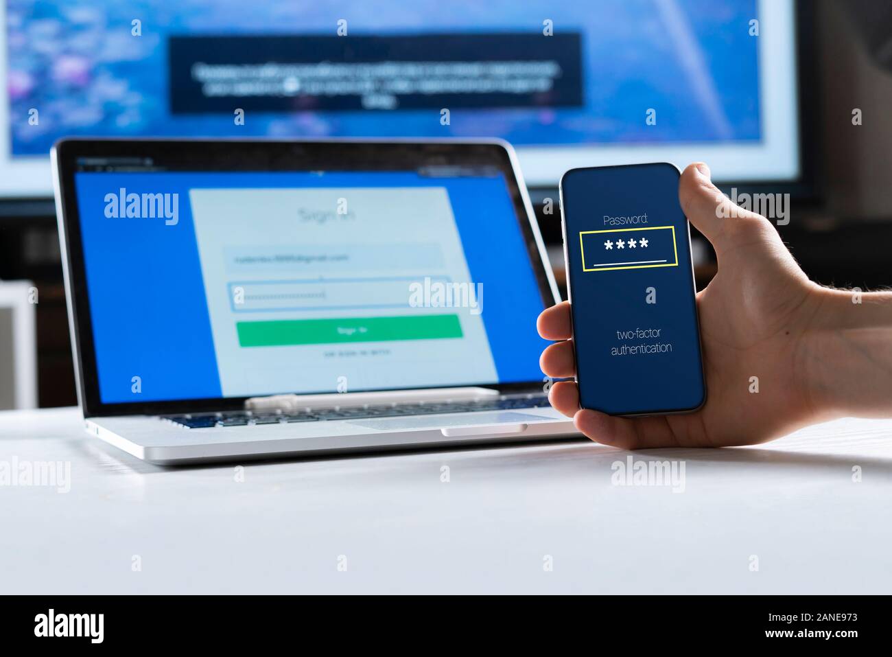 holding a phone and working using laptop, log in on website, double-factor authentication interface Stock Photo