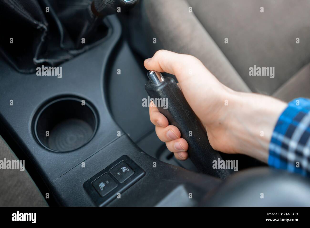 a close up cropped hand using the handbrake, driver sitting inside the
