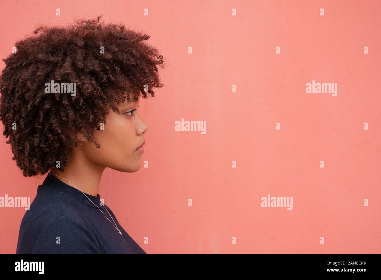Young woman with curly hair looking sideways against colorful background Stock Photo