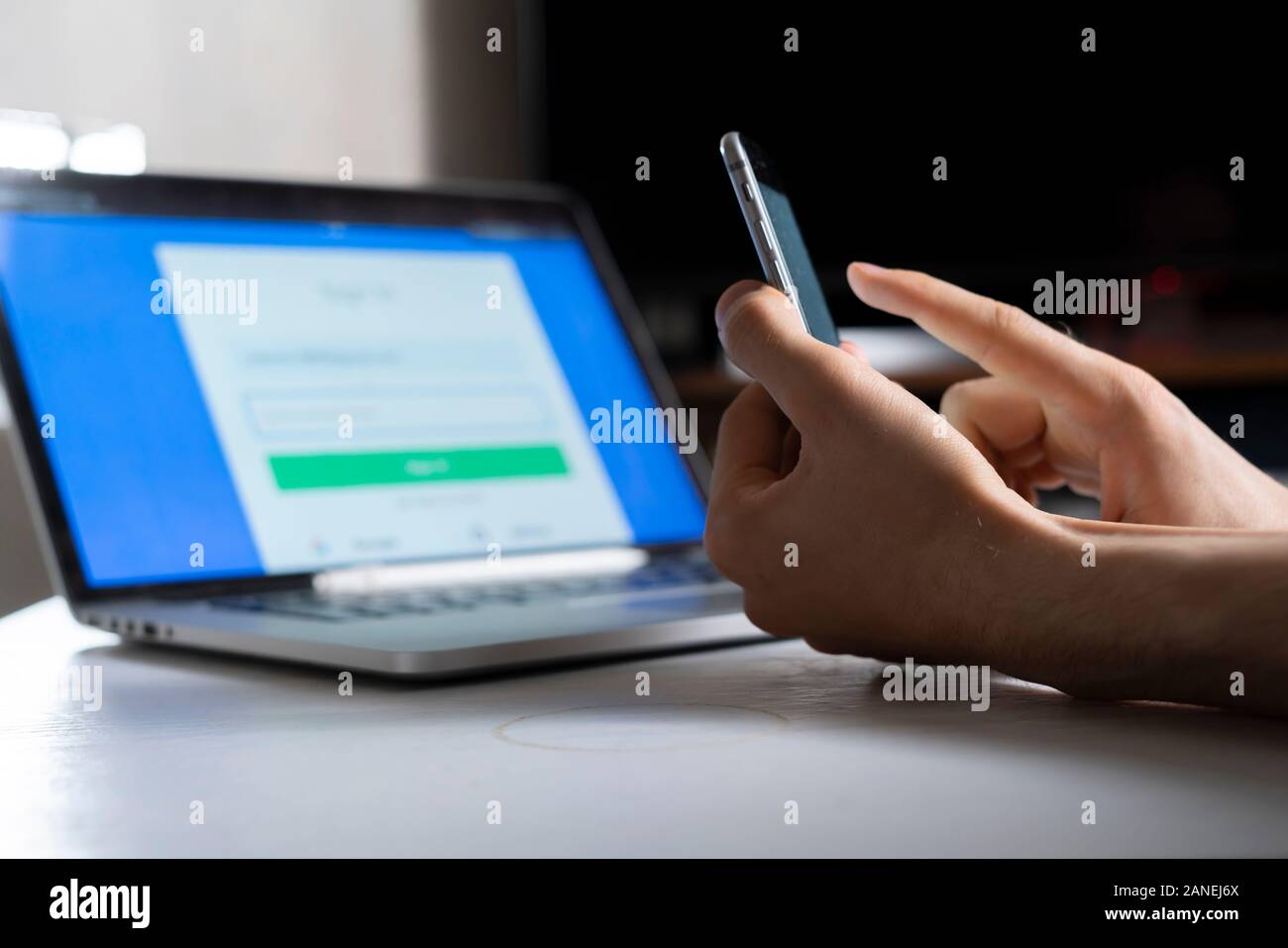 holding a phone and working using laptop, log in on website, double-factor authentication interface Stock Photo