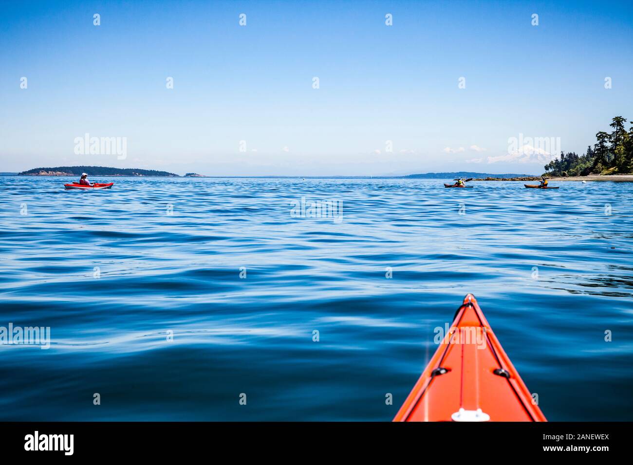 Sea kayaking of the North side of Orcas Island at North Beach, Washington State, USA. That is Mount Baker in the distance. Stock Photo