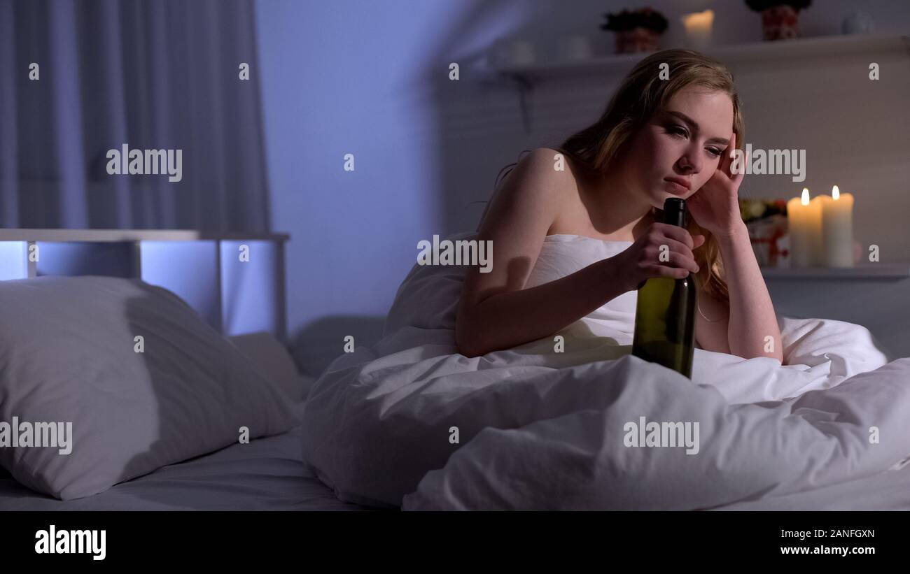 Drunk woman with wine bottle in bed, suffering hangover, alcohol addiction Stock Photo Alamy