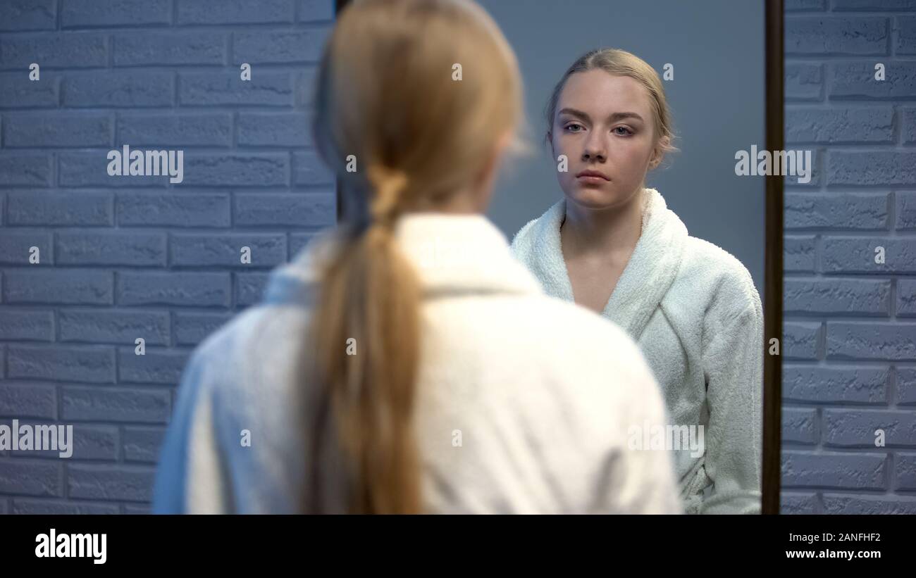 Unhappy young lady in bathrobe suffering stress looking in mirror, soul pain Stock Photo