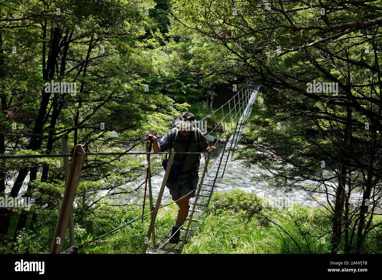 A wire swing bridge goes over a river in New Zealand Stock Photo