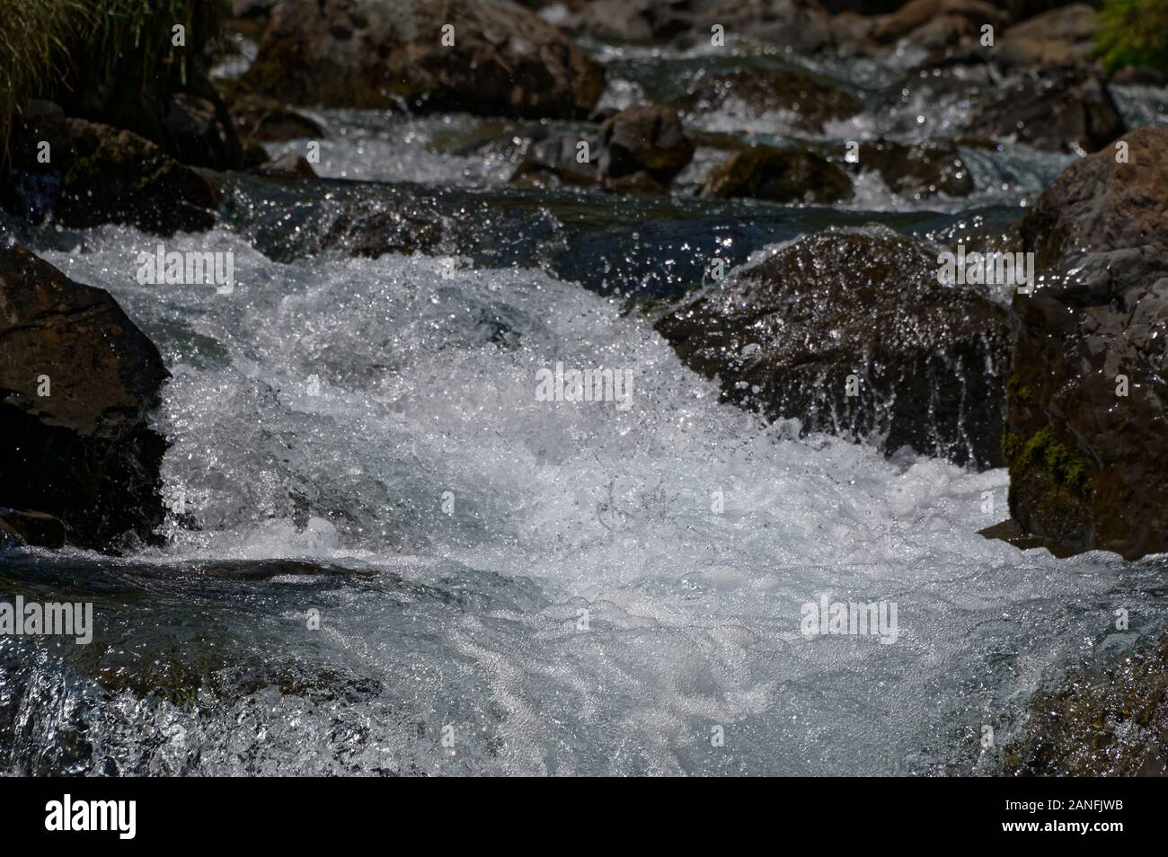 A river bed has frothy, white water from the flow of the water Stock Photo