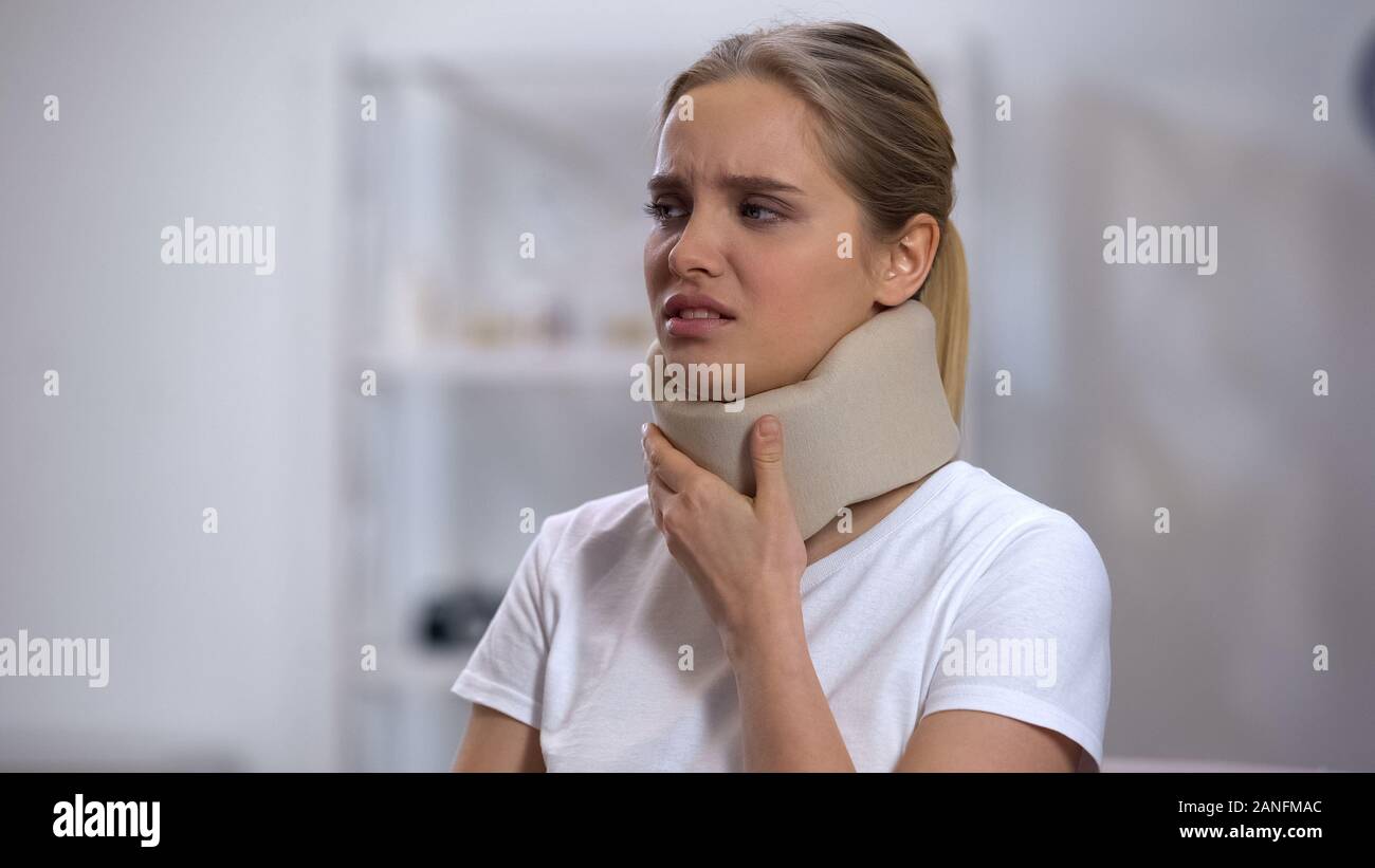 Girl in foam cervical collar touching neck, suffering from pain, recovery Stock Photo