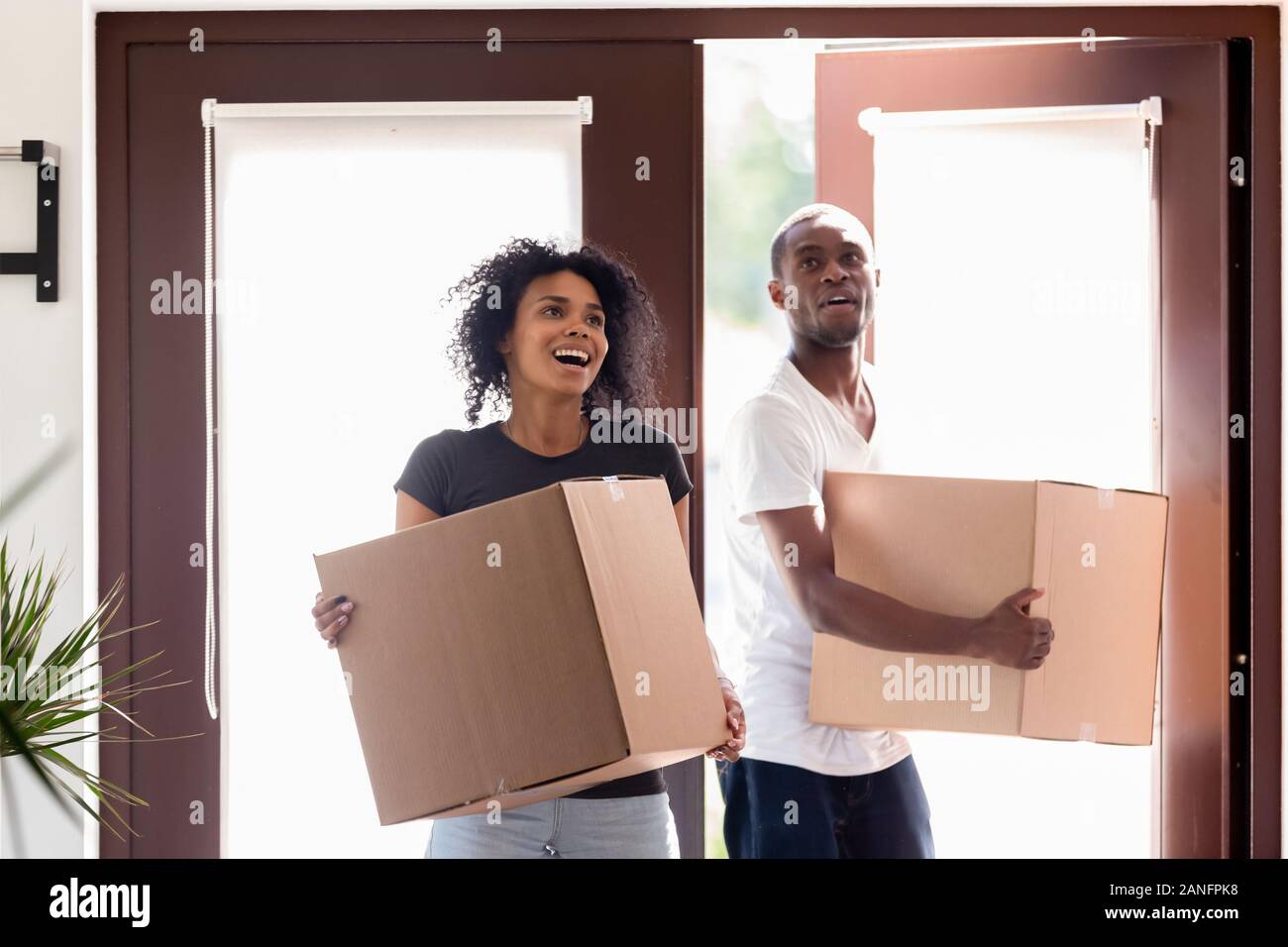 Excited black couple carrying boxes impressed entering new home Stock Photo