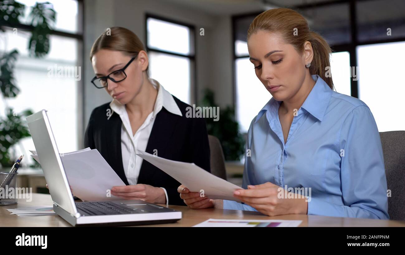 Boss reading report of trainee, dissatisfied with low rates, pressure at work Stock Photo