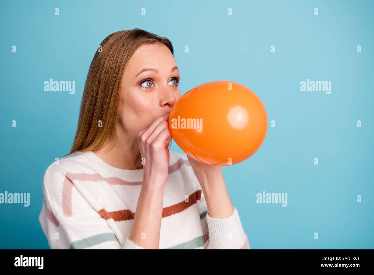 Turned close up photo of cheerful positive cute pretty woman feeling like child blowing air ball looking into empty space isolated pastel blue color Stock Photo