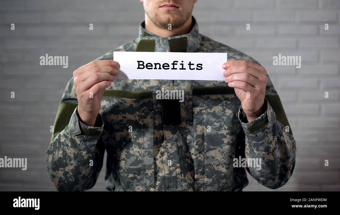 Benefits word written on sign in hands of male soldier, veterans support, aid Stock Photo Alamy