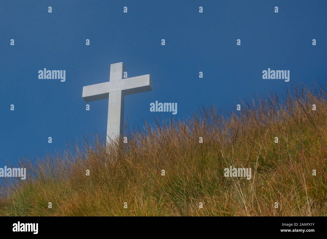 White religious cross against the blue sky and located on the peak of Mount Lema in Switzerland. This is a symbol of hope and salvation Stock Photo