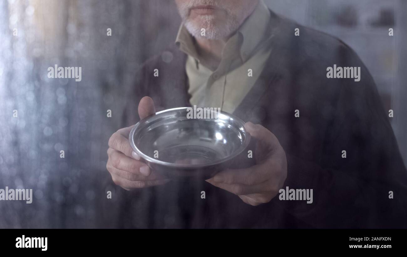 Poor elderly man showing empty bowl, low social allowance, lack of money Stock Photo