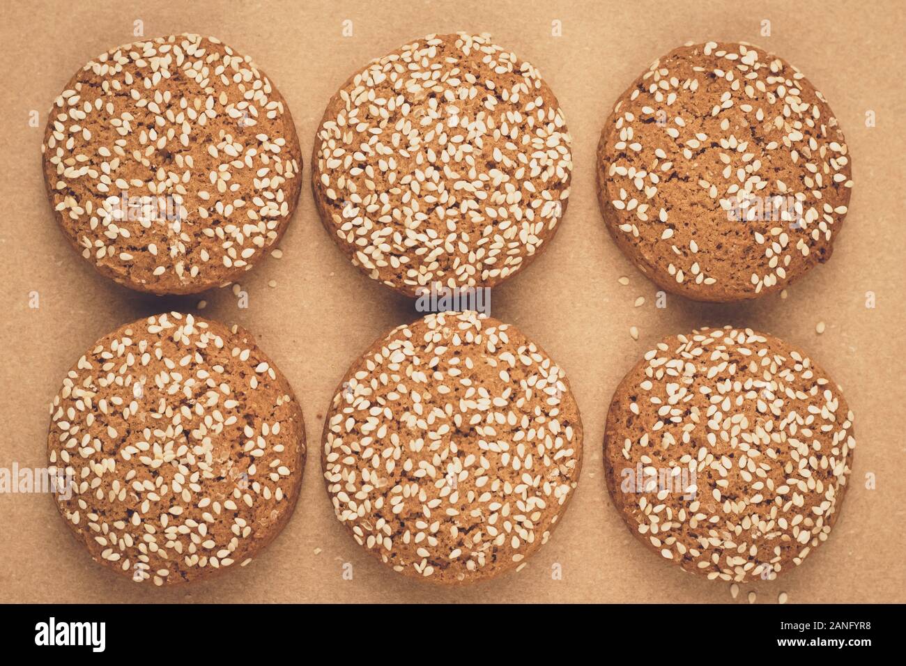 Oatmeal cookies on baking paper. Handmade bakery with sesame seeds. Brown background. A group of biscuits Stock Photo
