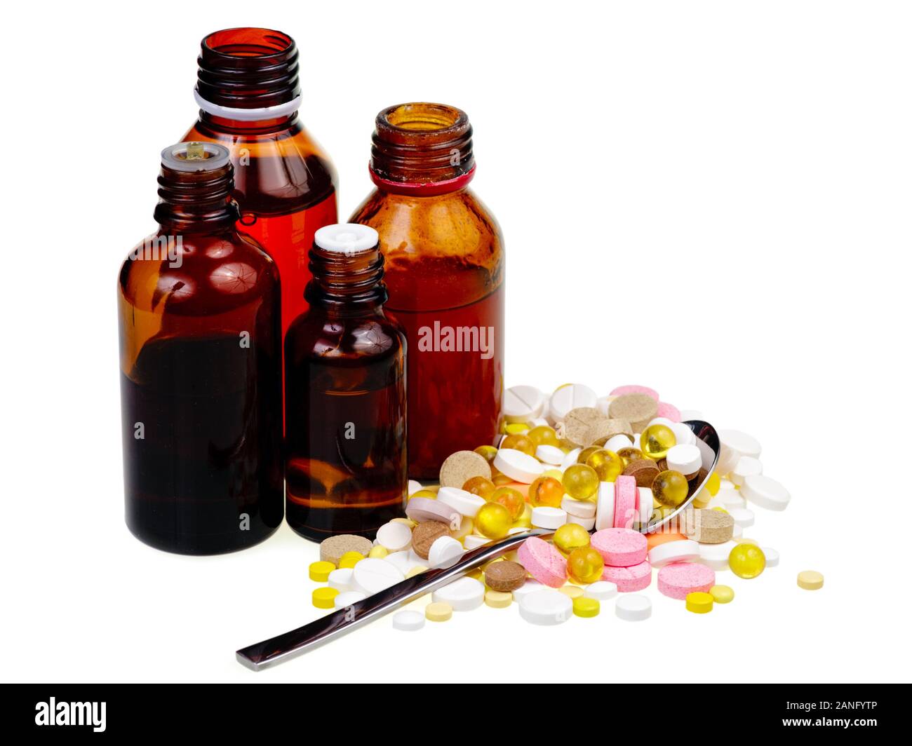 Open brown vials beside spoon  overfilled with pills Stock Photo