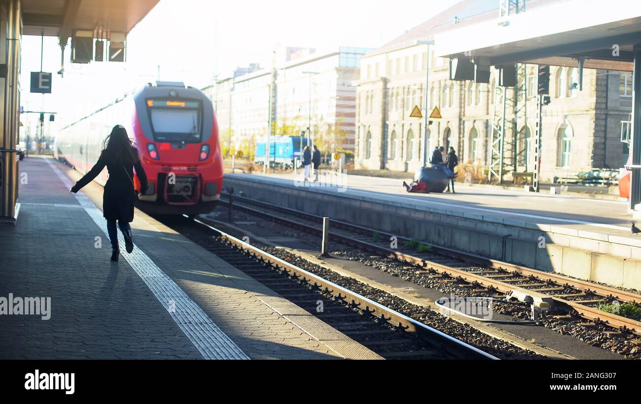 Lady late for train, running on platform, life in modern city, time-management Stock Photo