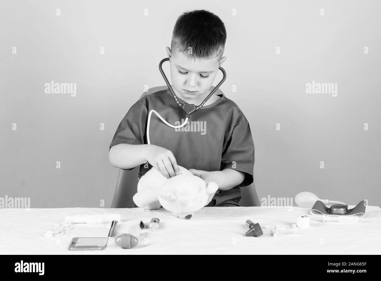 Health care. Kid little doctor busy sit table with medical tools. Medical examination. Medicine concept. Medical procedures for teddy bear. Boy cute c Stock Photo