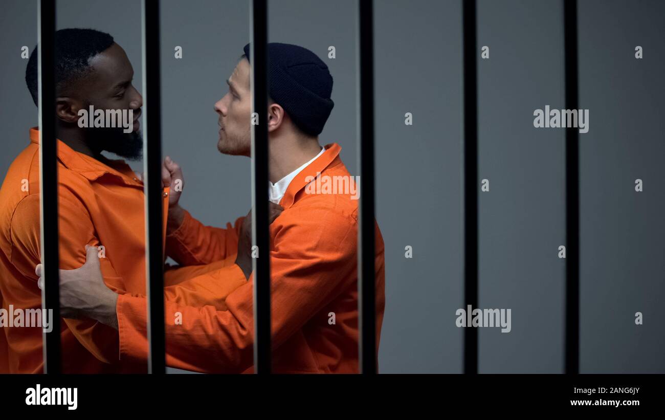 Caucasian prisoner fighting with black inmate, discrimination, jail overcrowding Stock Photo