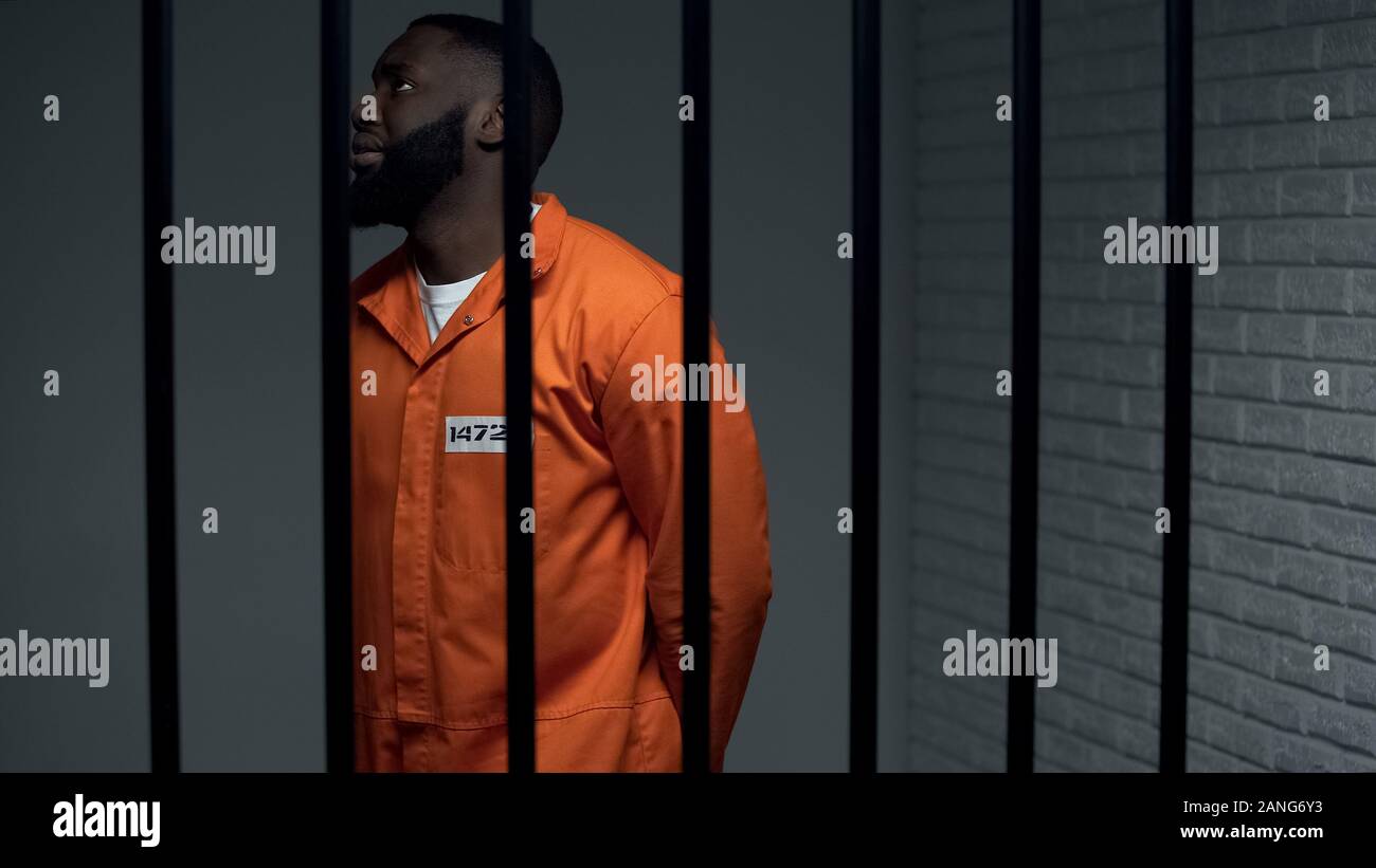 Nervous black prisoner waiting sentence in solitary cell, convicted criminal Stock Photo