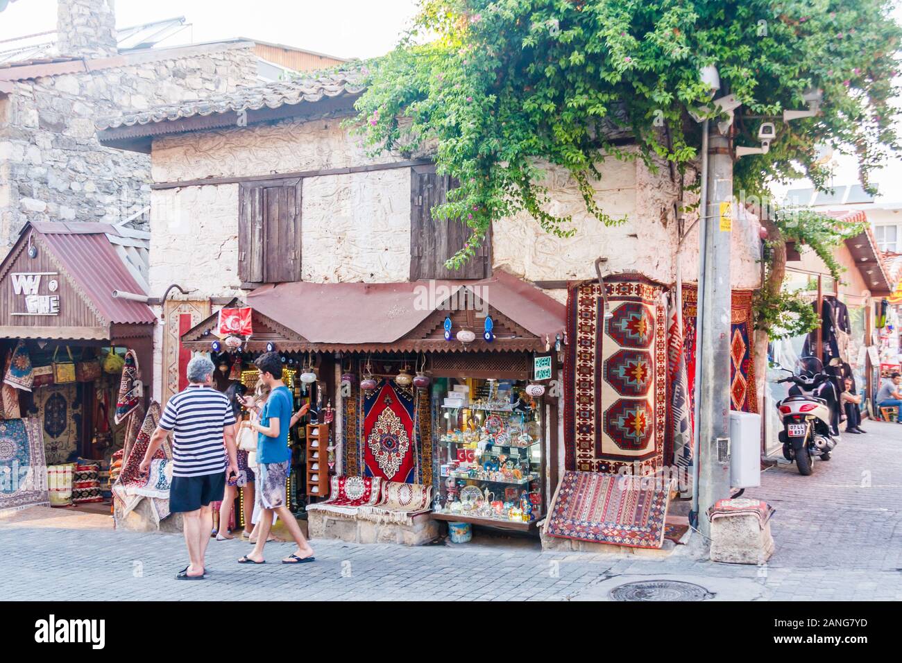 Side, Turkey - September 9th 2011: Tourists walking past a shop selling souvenirs and carpets. The town is a popular tourist destination. Stock Photo
