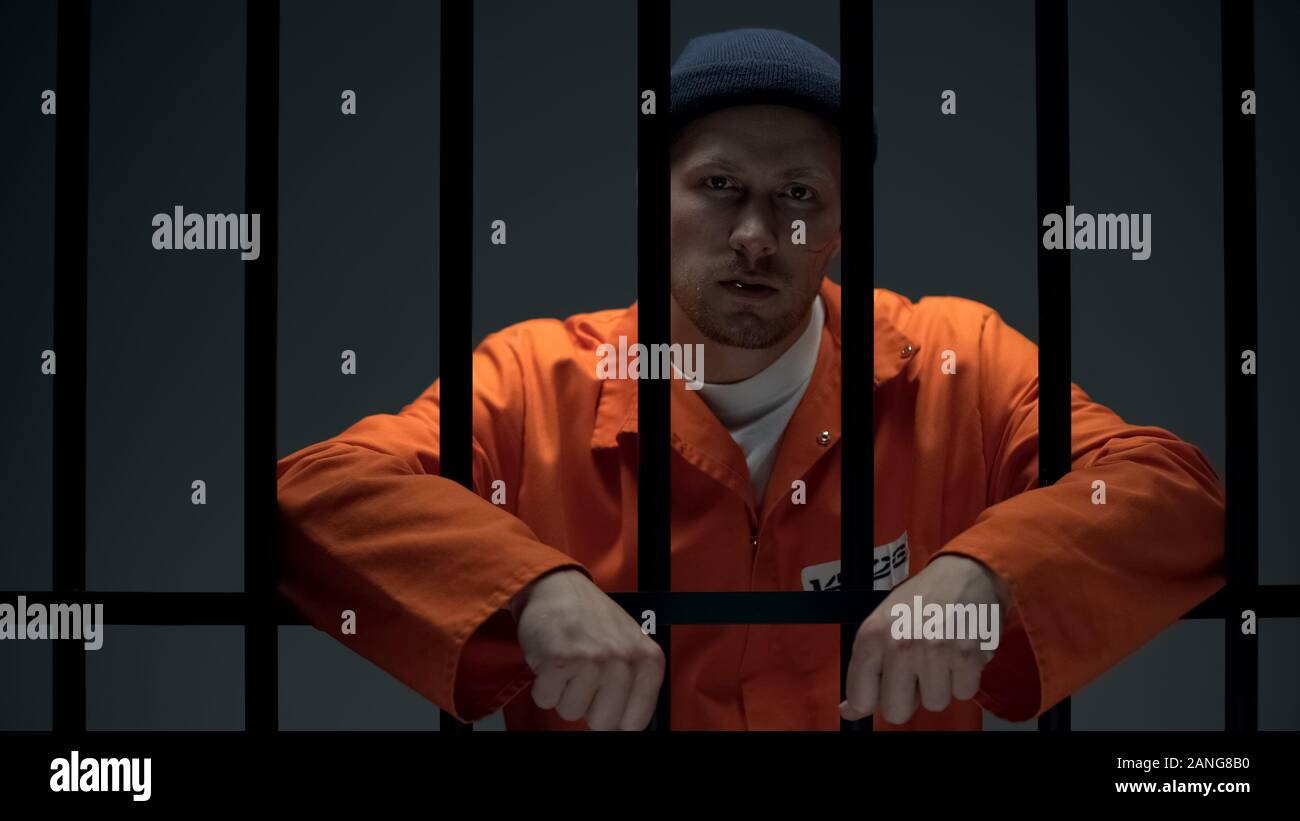 Dangerous imprisoned criminal splitting toothpick on floor and looking