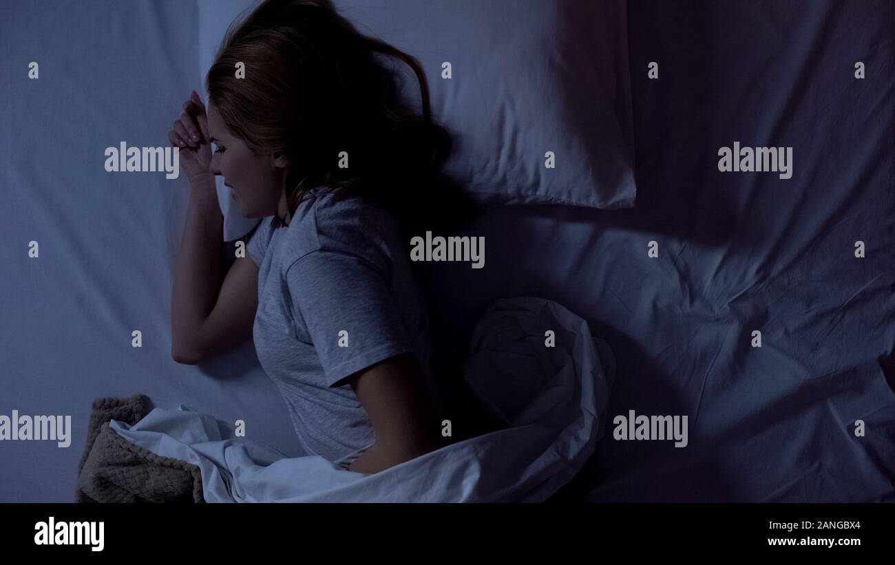 Lady feeling sharp stomachache during sleeping, suffering from cystitis illness Stock Photo