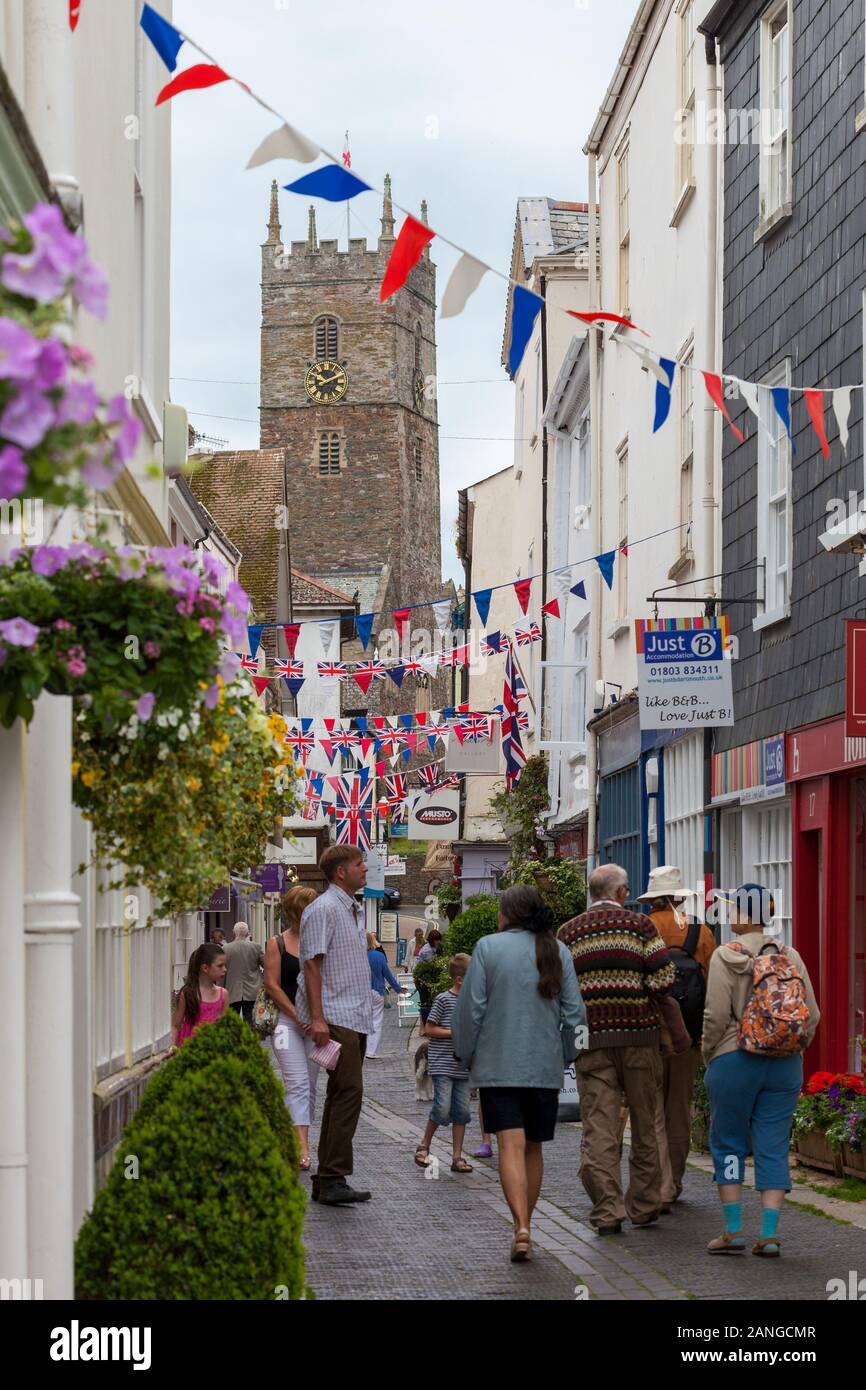 DARTMOUTH, UNITED KINGDOM - JUNE 1, 2012 : People walking along Foss Street, a popular shopping area in Dartmouth, with St Saviour's Church in the bac Stock Photo