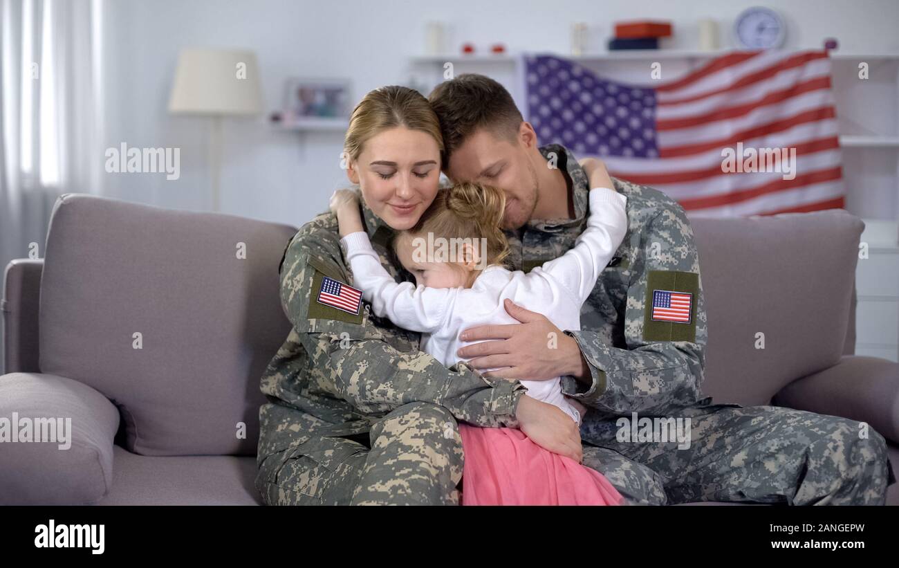 Cheerful little girl embracing US soldiers parents, family reunion, homecome Stock Photo