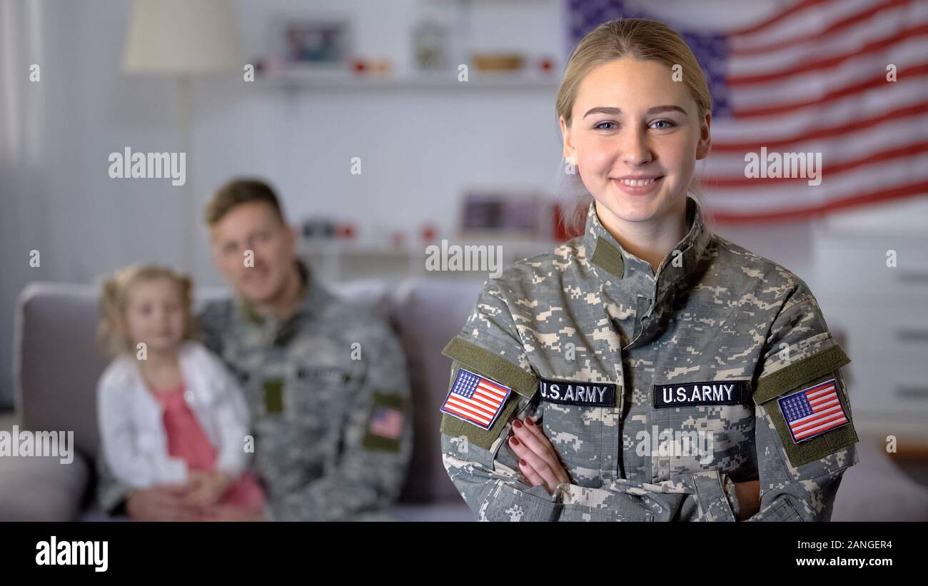 Smiling US female soldier looking at camera, husband and daughter admiring mom Stock Photo