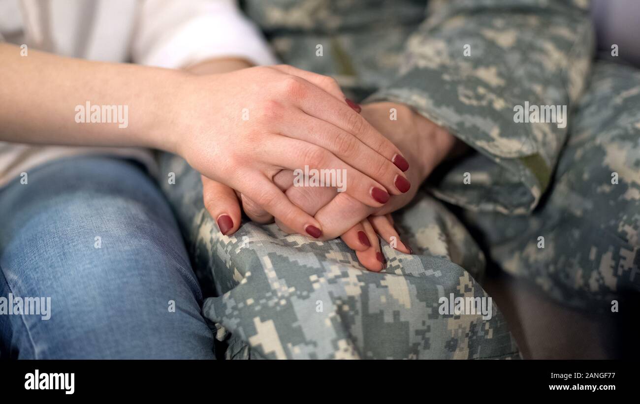 Military man and girlfriend holding hands, supporting boyfriend before leaving Stock Photo