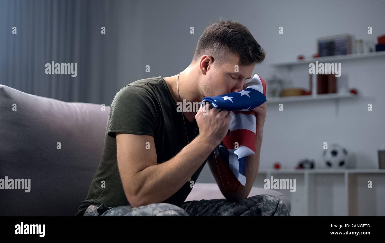 Male soldier kissing folded USA flag, preparing to comrade funeral, melancholy Stock Photo