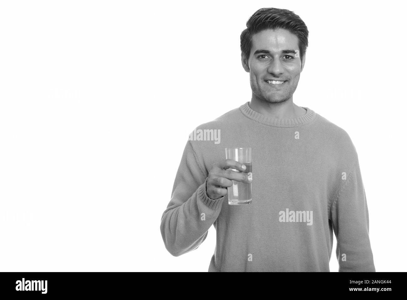 Young happy Persian man holding glass of water Stock Photo