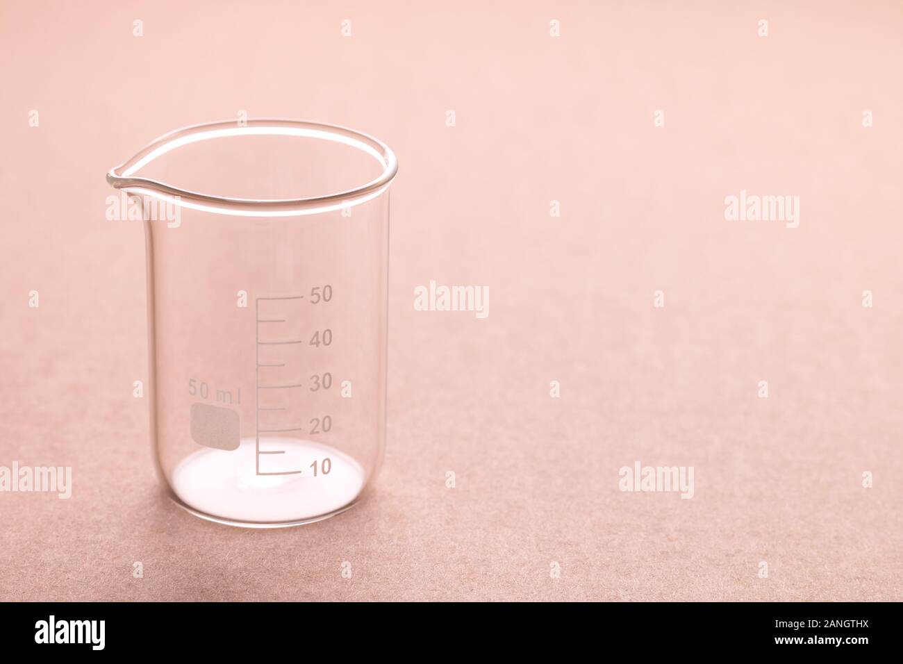 an empty clean glass 50 ml beaker on a rough brown surface Stock Photo