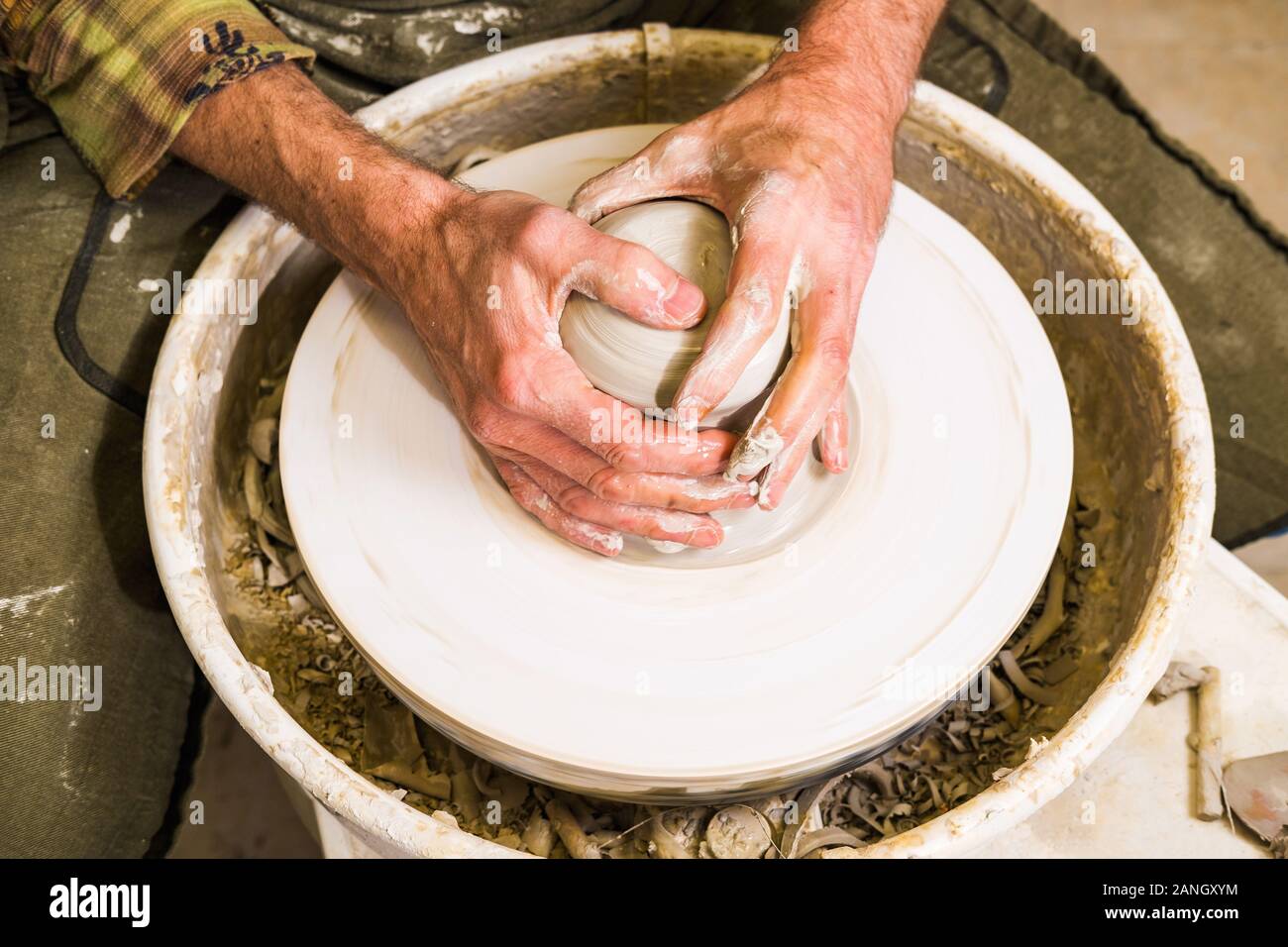 Potter making clay bowl or vase ceramics on the potter's wheel. Creating pottery art and handicraft modelling creation. Arms detail. Stock Photo