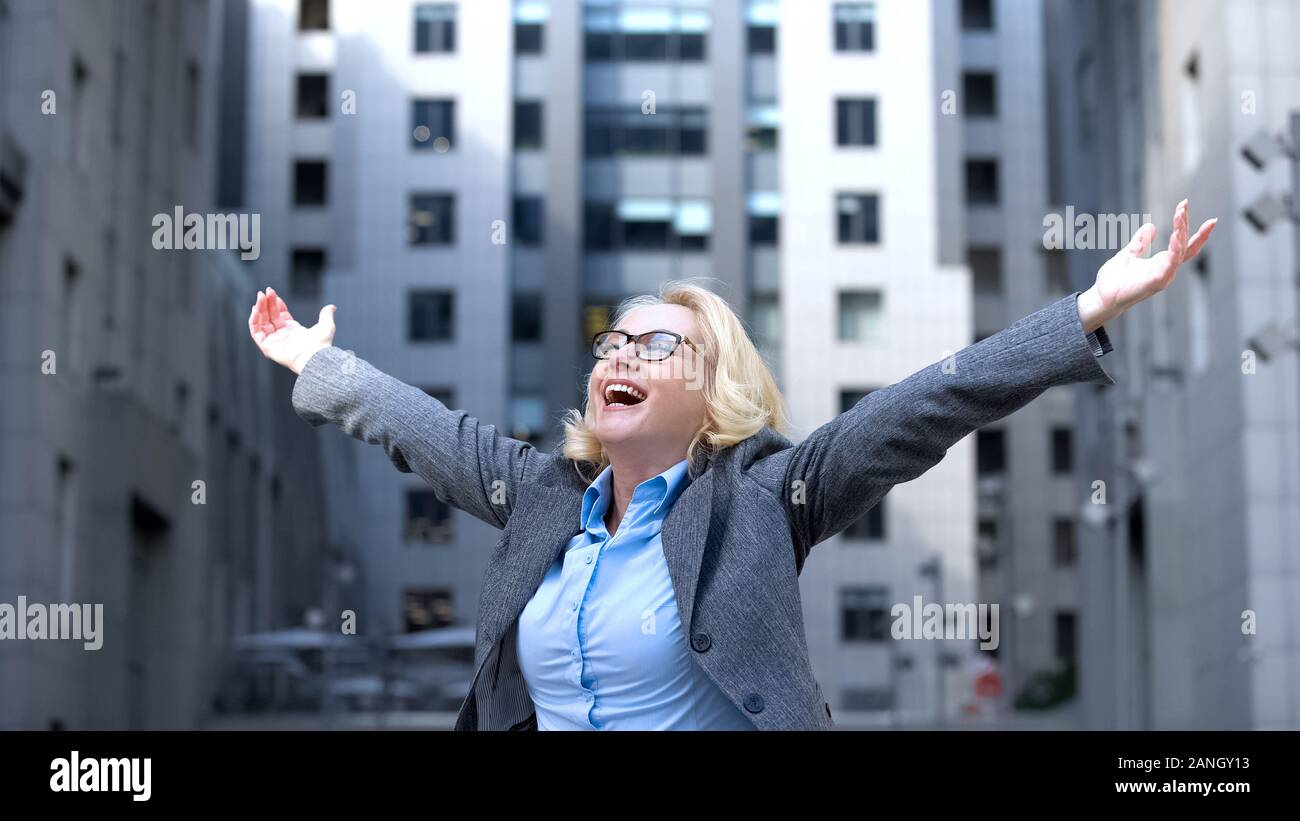 Optimistic elderly female raised hands enjoying life, business success, vitality Stock Photo