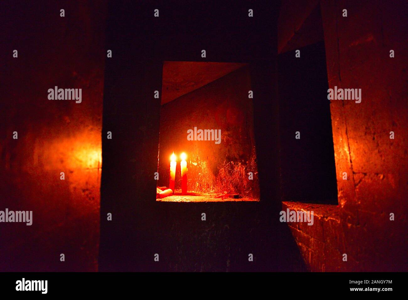 Candles burning inside mysterious in dark cave of Buddhist temple. Stock Photo