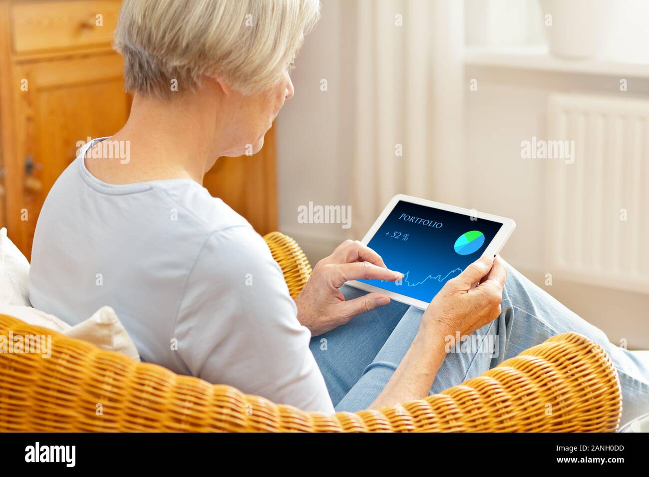 Senior woman in her living room checking her investment portfolio on a tablet computer. Stock Photo