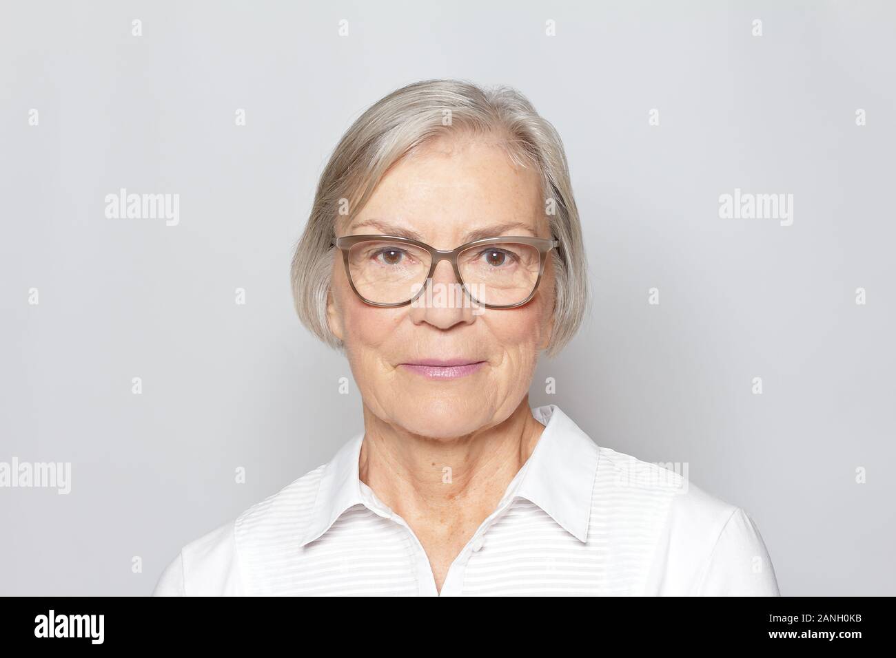 Portrait picture of a senior woman wearing glasses on neutral gray background. Stock Photo