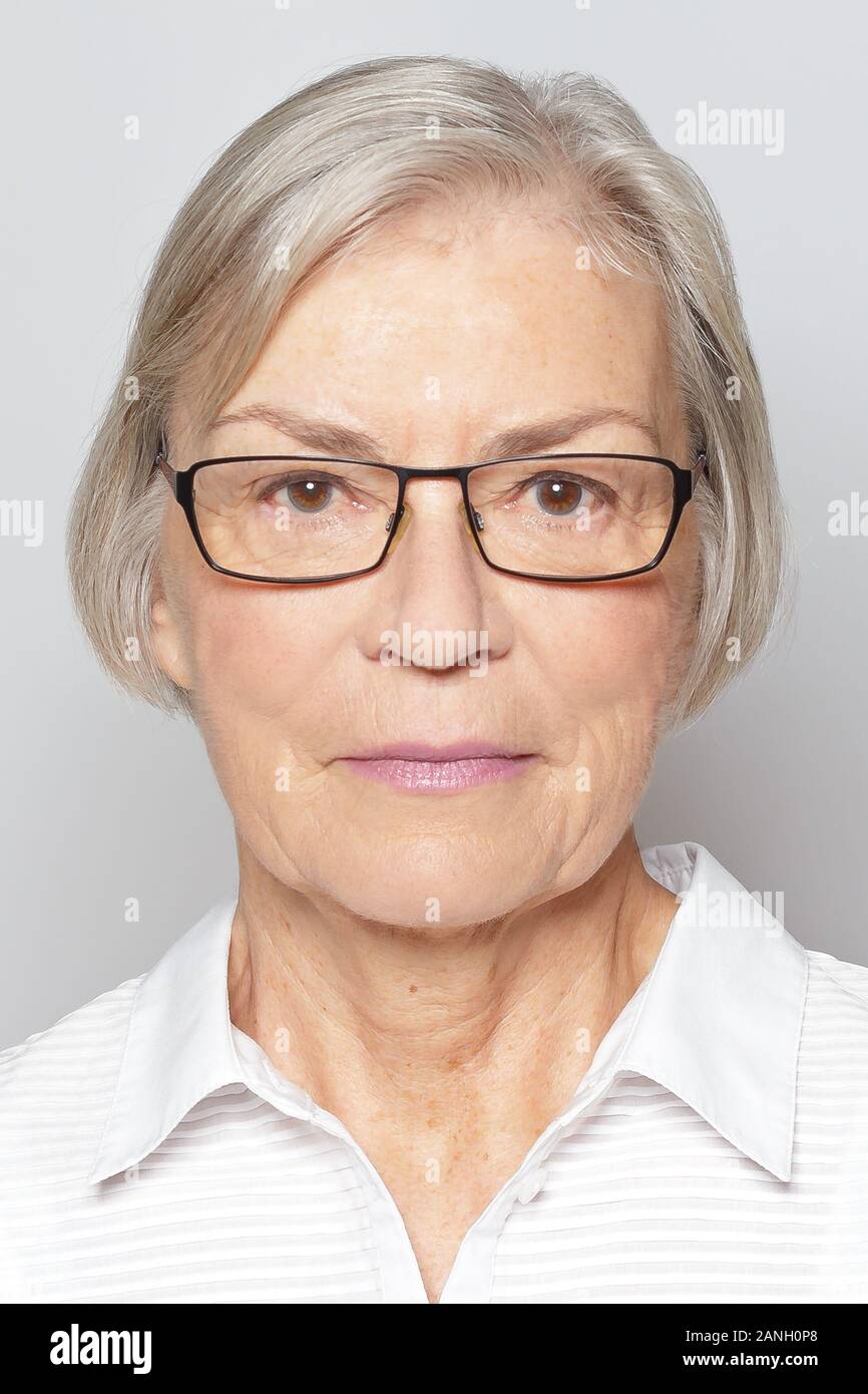 Biometric passport photo of a senior woman with glasses, neutral gray background. Stock Photo